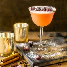 a drink in a goblet on a tray with cinnamons and anisette