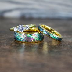 two gold wedding rings with colorful designs on them