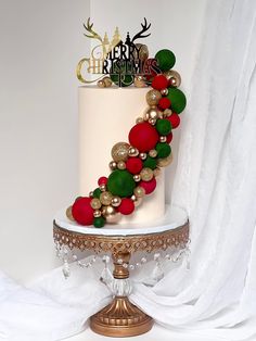 a white and gold christmas cake with red, green and gold baubles on top