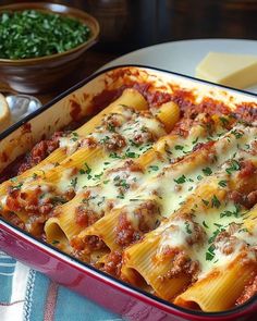 a casserole dish with meat, cheese and sauce in it on a table