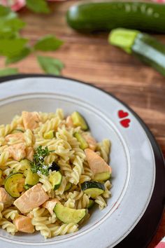 a white plate topped with pasta and veggies on top of a wooden table