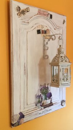 an old white door with a lantern and flowers on the ledge next to it is painted yellow