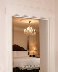 an open door leading to a bedroom with a bed and chandelier in it