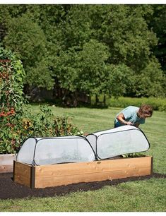 a man is working in the garden with his raised planter box and cover over it