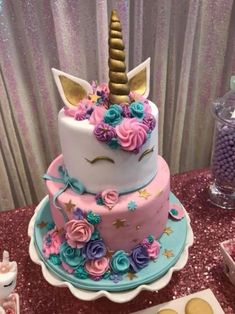 there is a cake decorated with flowers and a unicorn horn on the top, along with other desserts