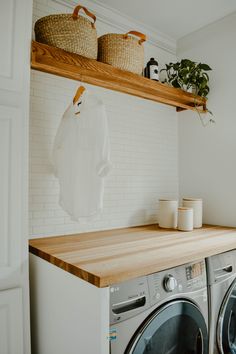 a washer and dryer sitting next to each other on top of a wooden shelf