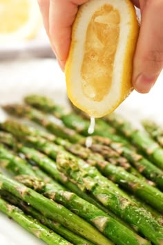 someone is squeezing lemon into asparagus on a plate