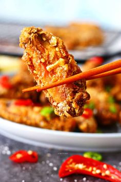 two chopsticks holding up food in front of some red peppers on the table