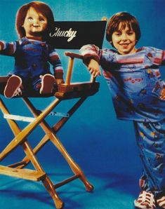 two children sitting in chairs with one holding a sign that says chucky and the other has