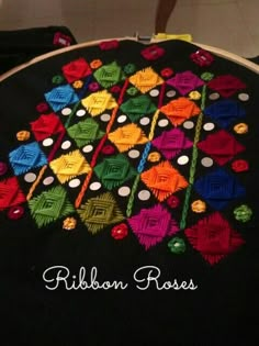 a close up of a black cloth with colorful designs on it and the words ribbon roses written in white