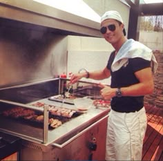 a man standing in front of an outdoor grill cooking food