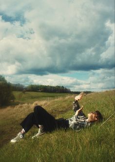 a person laying in the grass with a kite above their head on a cloudy day