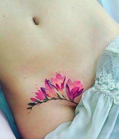 a woman's stomach with a pink flower tattoo on it