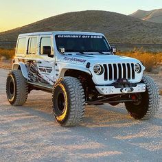 a white jeep is parked in the desert