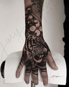 a person's hand with a tiger on it and flowers all over the palm