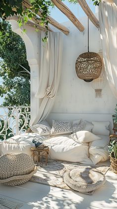 an outdoor seating area with pillows and wicker baskets hanging from the ceiling, surrounded by greenery