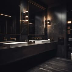 a bathroom with two sinks and mirrors in the dark, dimly lit room that has black walls