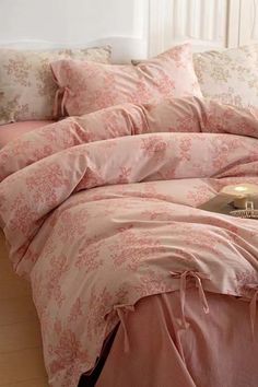 a bed with pink comforters and pillows on it