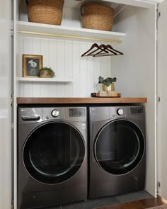 a washer and dryer in a laundry room with shelves above them, along with baskets on the wall