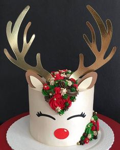 a white cake with gold antlers and red roses on top, sitting on a table