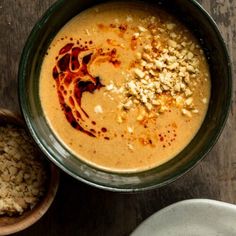 there is a bowl of soup on the table next to two bowls with food in it