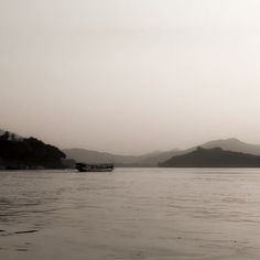 a boat floating on top of a large body of water next to a mountain range