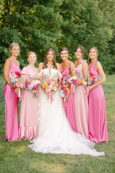 a group of women standing next to each other in pink dresses and holding bouquets