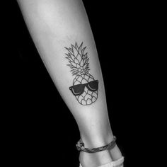 a pineapple with sunglasses tattoo on the leg and foot is seen in this black and white photo