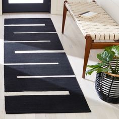 a black and white rug in a living room next to a chair with a potted plant on it