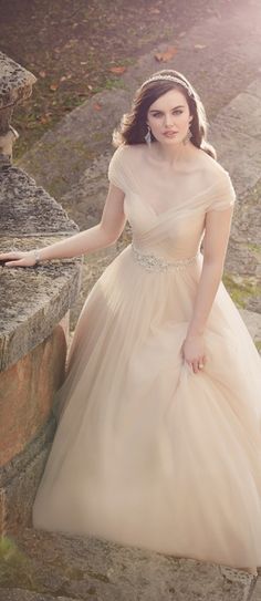 a woman in a wedding dress leaning against a stone wall