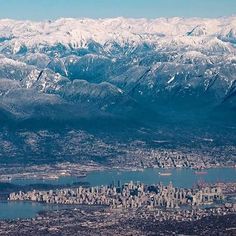 an aerial view of the city and mountains with snow covered peaks in the foreground