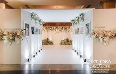 an indoor wedding ceremony with flowers and greenery on the wall at the end of the aisle