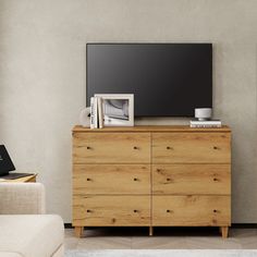 a living room with a television on top of a wooden dresser next to a couch