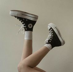 a woman in black and white converse shoes with her legs spread out to the side