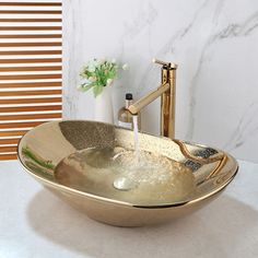 a gold bowl sink with water running from the faucet in front of it