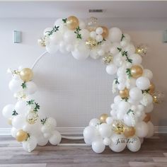 a white and gold balloon arch with greenery