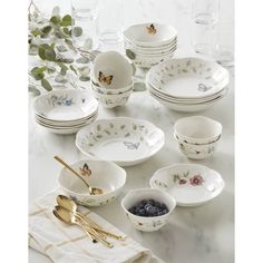 a table topped with lots of white plates and bowls filled with blueberries next to silverware