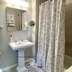 a white sink sitting under a bathroom mirror next to a bathtub and shower curtain