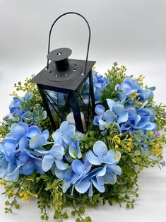 a black lantern with blue flowers around it