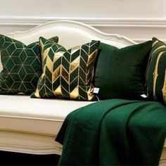 a white couch with green and gold pillows sitting on it's back cushiones