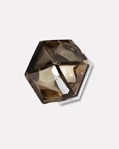 a brown diamond shaped object on a white surface with the light reflecting off it's face