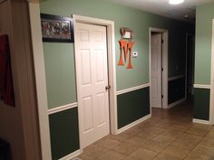 an empty hallway with green walls and white trim on the doors, carpeted floor