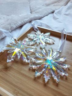 two crystal snowflakes sitting on top of a wooden table next to a white blanket