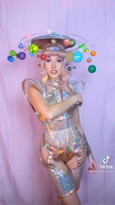 a woman dressed in shiny clothing and hat with bubbles coming out of her head, posing for the camera