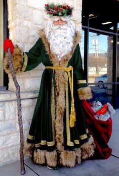 a man dressed as santa claus standing next to a building with a cane in his hand