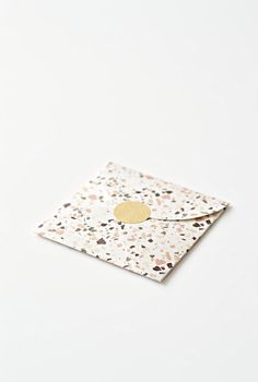 a white envelope with a gold circle on the front and black speckles around it