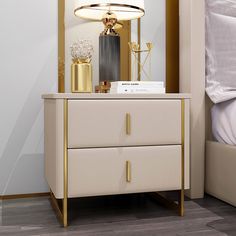 a white and gold nightstand with a lamp on top of it next to a bed