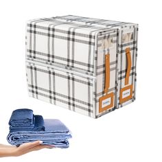 a stack of folded clothes next to a hand holding one piece of blue and white plaid fabric