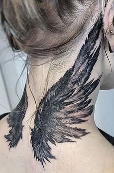 the back of a woman's neck is covered with black feathers and has a tattoo design on it