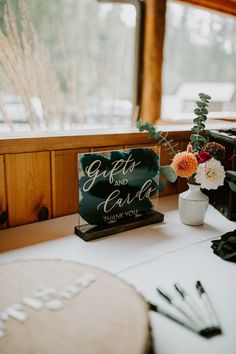 a sign that says gifts and cards are sitting on a table next to some flowers